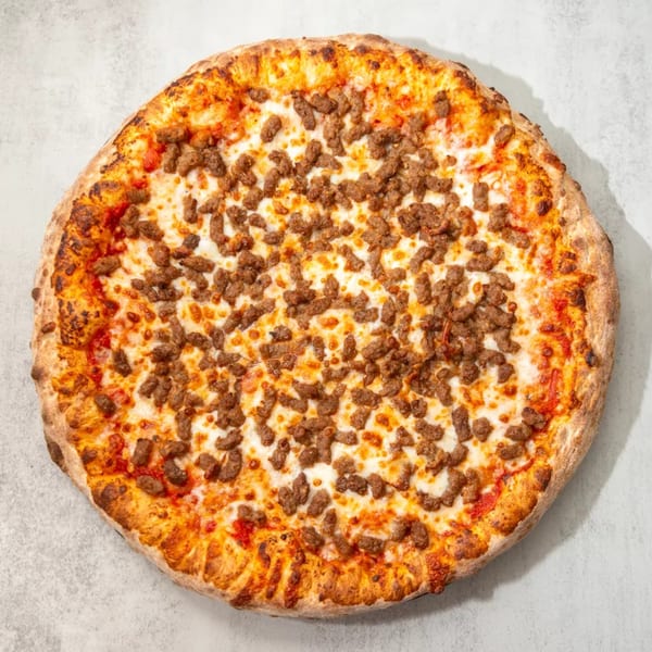A whole sausage pizza with melted cheese and a crispy crust on a light gray surface.
